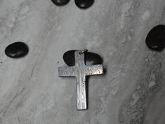 Introducing our exquisite Damasteel cross pendant (Large) - a one-of-a-kind piece of jewelry handcrafted with impeccable attention to detail. Made from the finest quality Damasteel, this unique pendant showcases a mesmerizing pattern created through a complex process of layering and forging multiple types of stainless steel. The sleek and simple design allows the beauty of the Damasteel to be the focal point, making it a versatile accessory that can be dressed up or down.  The nature of the Damasteel material from which this pendant is crafted ensures a unique and one-of-a-kind piece to treasure for years to come. Invest in luxury and craftsmanship with our Damasteel cross pendant - a true symbol of quality and style. We offer several hanging options with all our pendants.  The options we Distinctive Cross Jewelry For Gifts, Handmade Cross Necklace For Gift, Polished Cross Jewelry As A Gift, Artisan Cross Jewelry For Jewelry Making, Unique Cross Jewelry For Gifts, Polished Pendant Cross Necklace As Gift, Unique Cross Jewelry As Gift, Artisan Cross Pendant Necklace As Gift, Artisan Cross Necklace For Gift