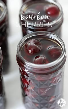 four jars filled with cherries sitting on top of a table next to each other