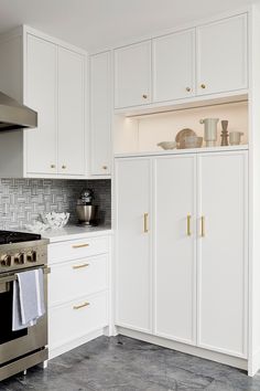 a kitchen with white cabinets and stainless steel stove top oven in the middle of it