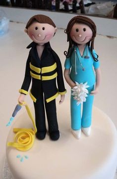 two cake toppers are standing next to each other on a white table with blue and yellow icing