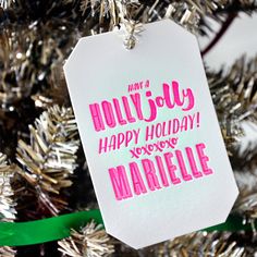 a christmas ornament hanging from the top of a tree with pink writing on it