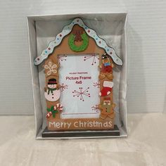 a gingerbread house frame with christmas decorations on the front and sides, in a clear box