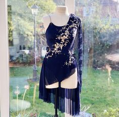 a mannequin wearing a dress on display in front of a window with grass and flowers