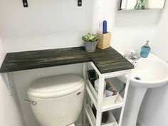 a white toilet sitting next to a sink under a wooden counter top in a bathroom