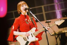 a woman singing into a microphone while holding a guitar