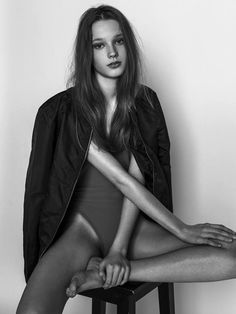 a woman sitting on top of a stool in a black and white photo with her legs crossed