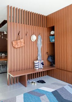 a wooden bench sitting in the middle of a room next to a wall with shoes on it