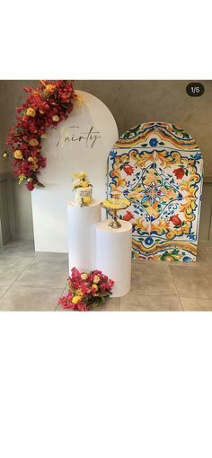 two rolls of toilet paper sitting on top of a tile floor next to a vase with flowers