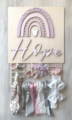 a wooden sign that says hope with lots of baby clothes hanging from it's hooks