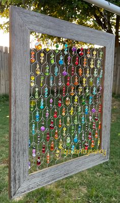 a wooden frame with many different colored beads hanging from it's sides in the grass