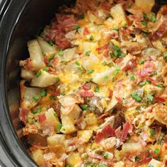 a crock pot filled with potatoes and meat, garnished with green onions