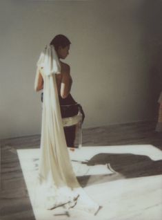 a woman in a wedding dress standing on the floor with her back to the camera