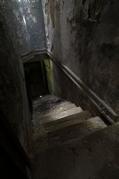 the stairs are made of concrete and have graffiti on them in an abandoned building with light coming through