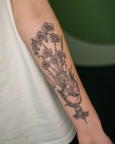 a woman's arm with flowers and birds tattoo on the left side of her arm