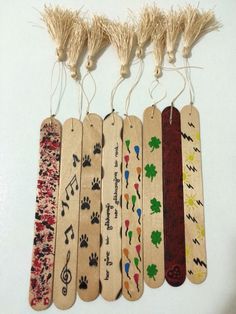 five wooden bookmarks with different designs on them hanging from strings and tassels