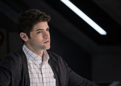 a man sitting at a table in front of a laptop computer and looking off to the side