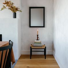 a small table with a candle on it next to a mirror and chair in a room