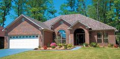 a brick house with two garages in the front yard and green grass on both sides