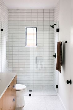 a bathroom with a toilet, sink and shower in it's own area that has white tiles on the walls