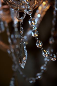 a crystal chandelier with beads hanging from it's sides and lights in the background