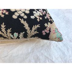 a black and pink floral pillow on a white sheet