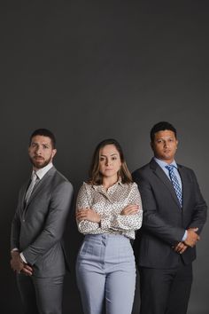 three people standing next to each other with their arms crossed and looking at the camera