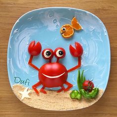 a plate with a crab on it and an orange fish in the water next to it