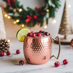 a copper mug filled with cranberries and lime on top of a marble counter