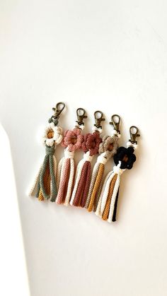 five tasseled key chains with flowers on them sitting next to eachother