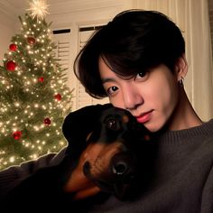 a person holding a dog in front of a christmas tree