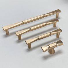 four brass handles and knobs on a white surface