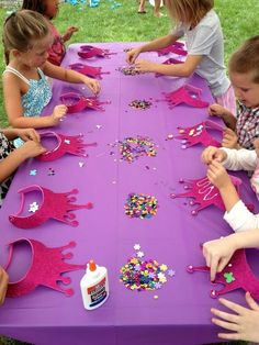 children are sitting at a purple table with pink decorations on it and confetti sprinkles all over the table