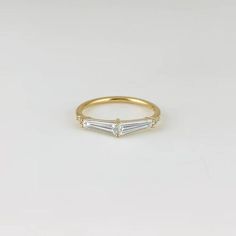 a yellow gold ring with two baguettes in the middle, on a white background