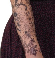 a woman's arm with flowers and dragonfly tattoo on her left arm, in front of a white background