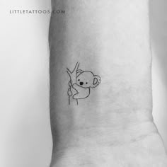 a small tattoo on the wrist of a person with a koala bear holding a branch