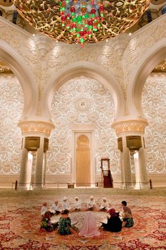 an elaborately decorated room with chandelier and rugs on the floor in front of two men sitting at a table