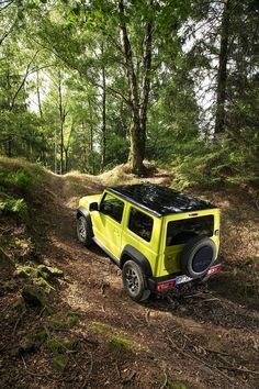 a yellow jeep driving down a dirt road in the woods