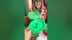 a person holding a green frisbee with the number one on it in front of them