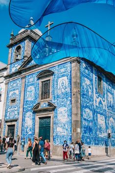 many people are walking around in front of a blue and white building with a crosswalk