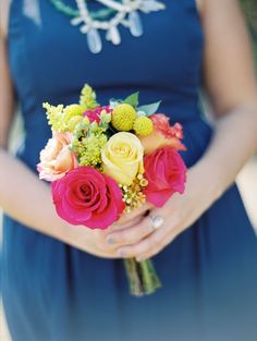 a woman in a blue dress holding a bouquet of roses and succulents