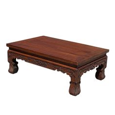 a wooden coffee table with carved legs and an intricate design on the top, against a white background