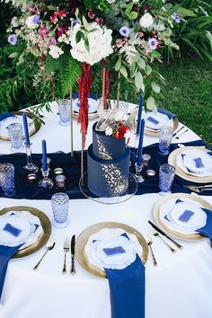 the table is set with blue and white place settings, silverware, and flowers