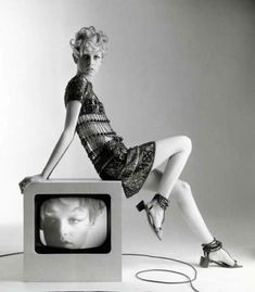 a black and white photo of a woman sitting on top of a tv