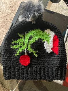 a crocheted hat with an image of the grin face on it, sitting on top of a table