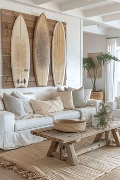 a living room filled with white furniture and surfboards on the wall above it's windows