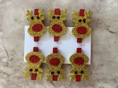 six reindeer head clips with red noses and gold glitters on white paper, sitting on a marble surface