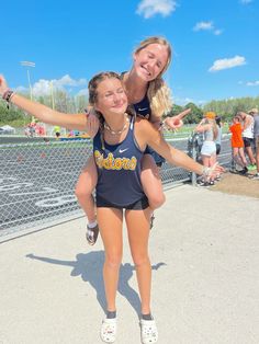 two girls are posing for the camera with their arms around each other in front of a fence