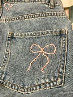 a pair of jeans with pink bows on the back pocket and an embroidered bow at the waist