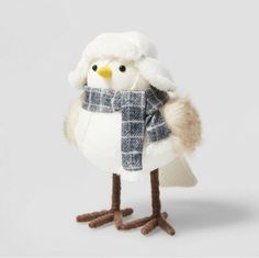 a stuffed bird with a scarf and hat on it's head, standing in front of a white background