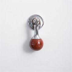 a door handle on a white wall with a red ball hanging from it's side